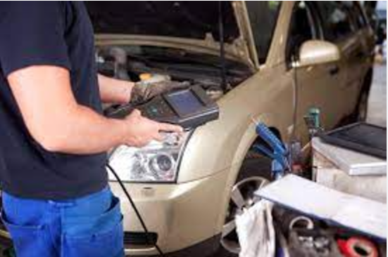 Technician using a handheld diagnostic scanner on a Ford vehicle in a workshop