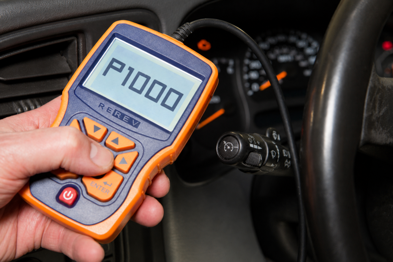 Handheld OBD scan tool displaying Ford code P1000 inside a vehicle